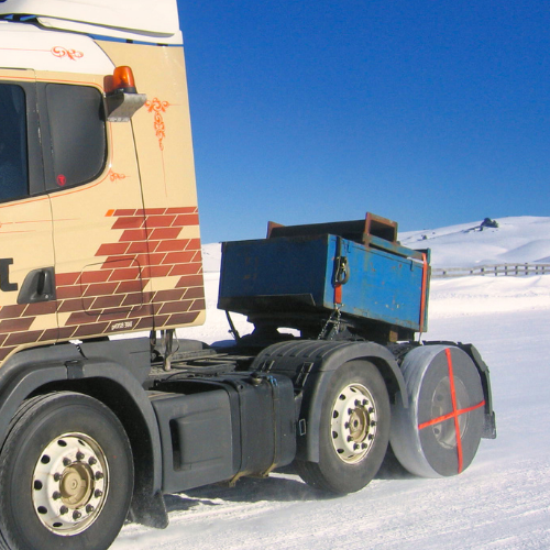 トラックの車輪に取り付けられたAutoSockタイヤソックス、冬の風景の雪の上を運転